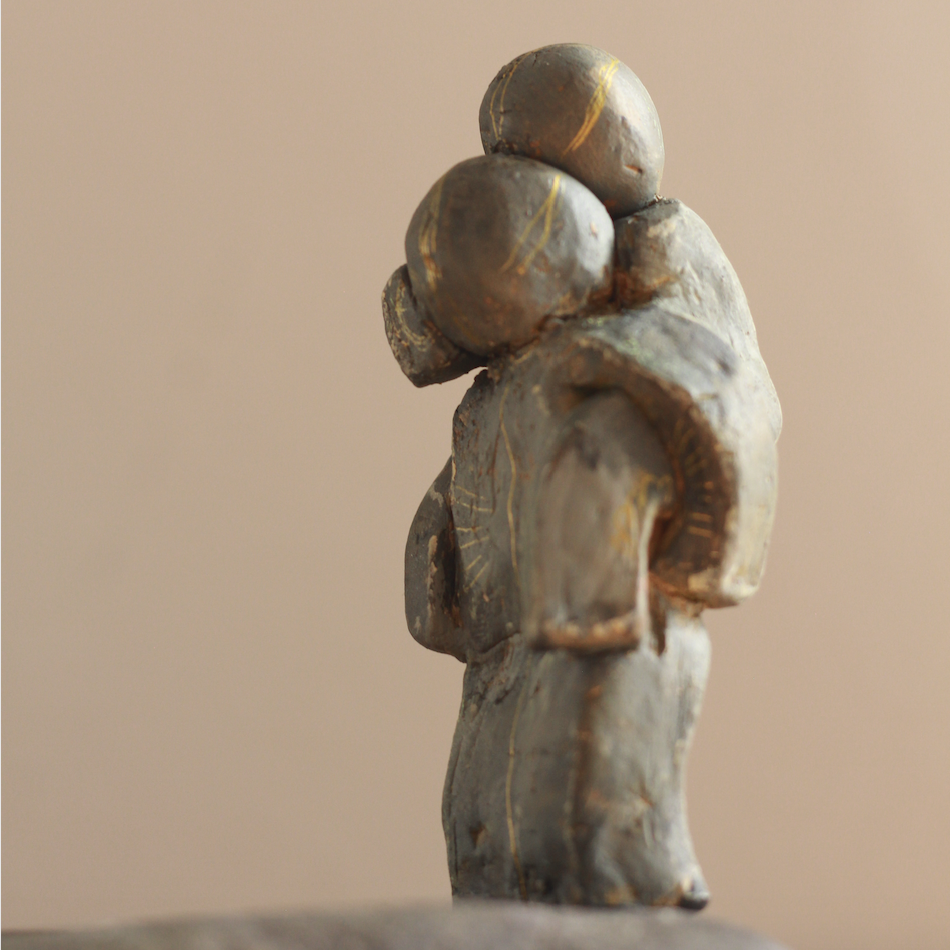 Small hand-made clay figure with a second, smaller figure on its shoulders and fine gold lines etched into the surface