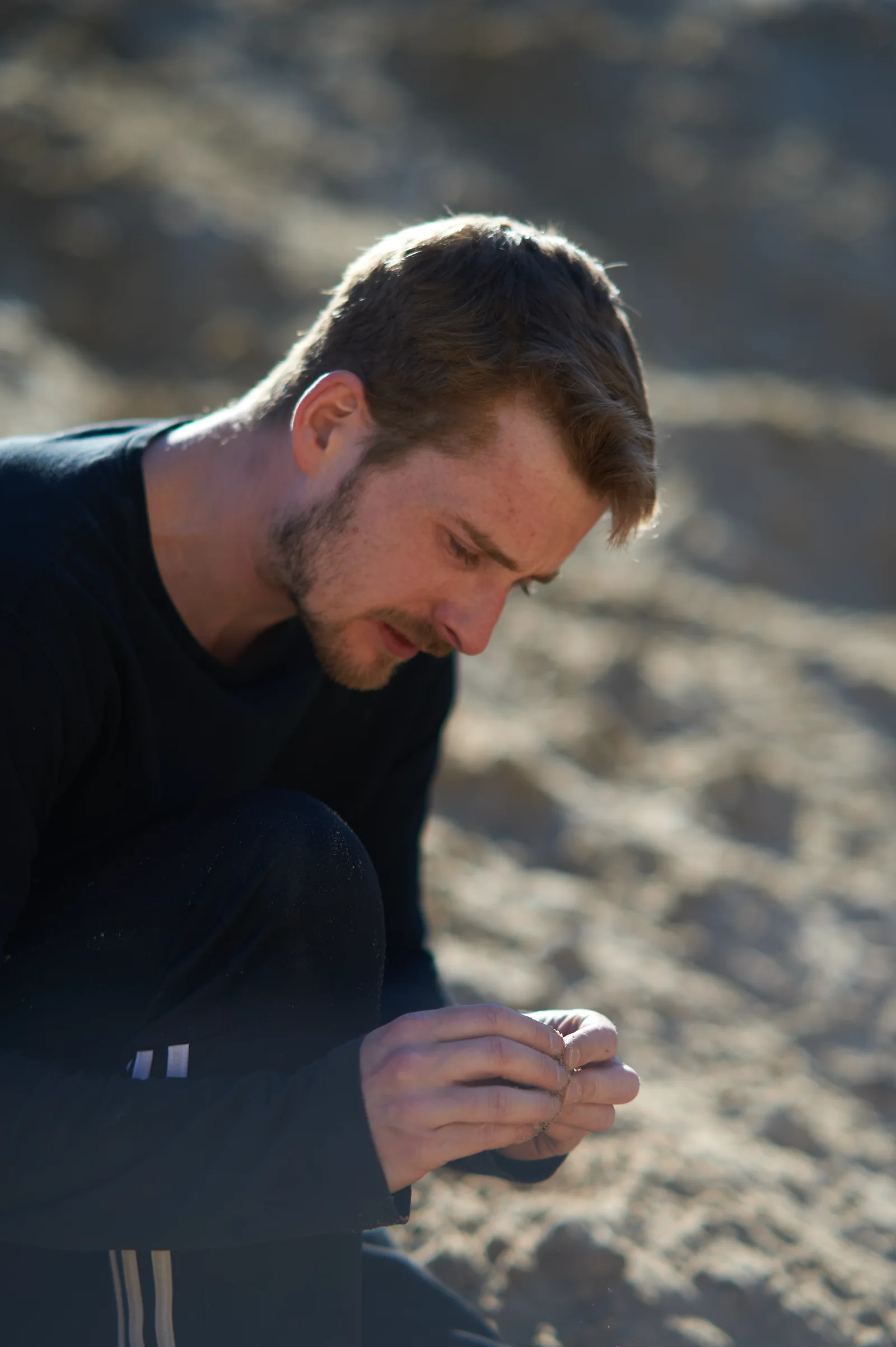 Sam kneeling and exploring sand with his hands